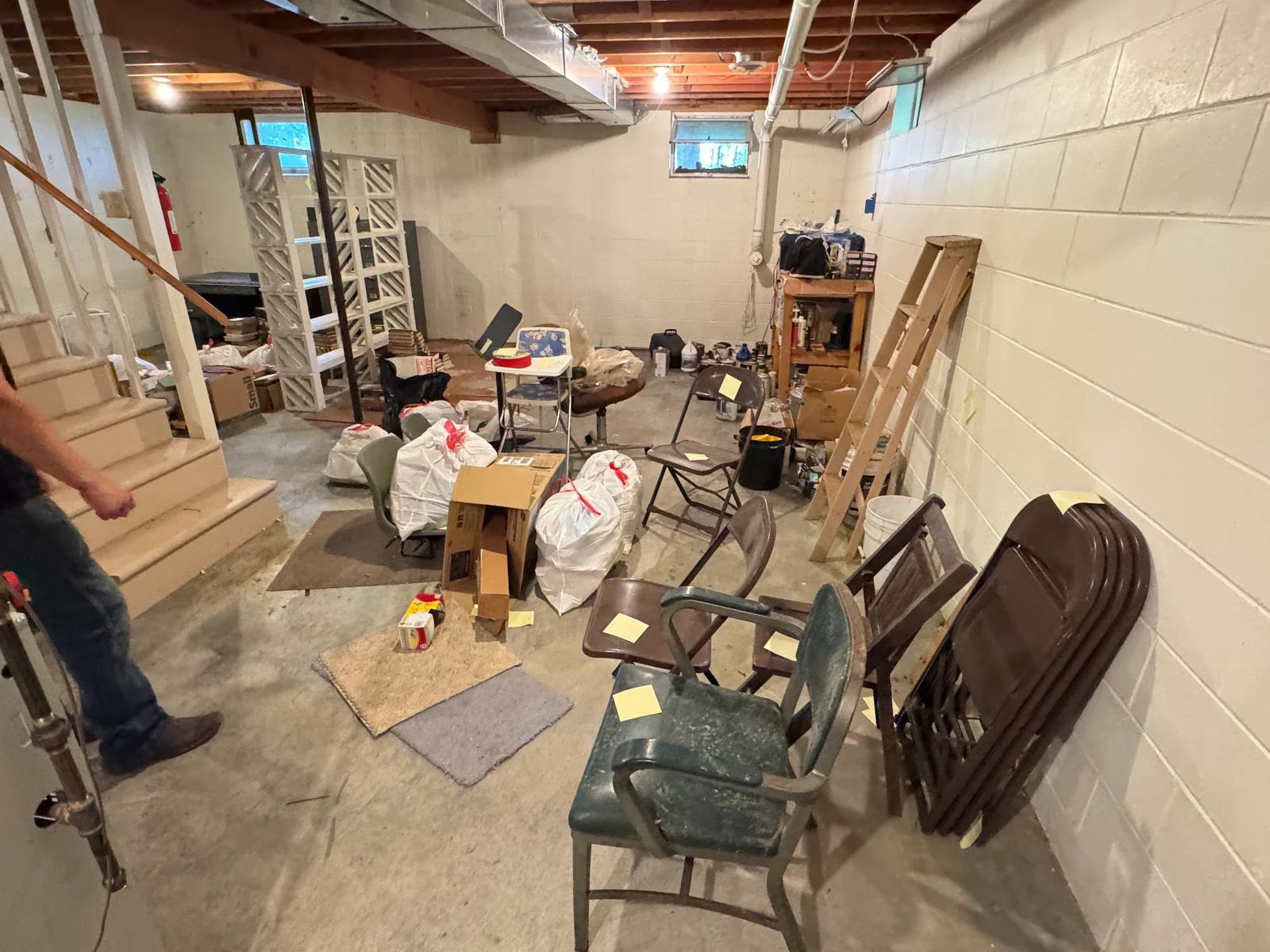 Basement full of folding chairs, tied contractor bags, cardboard boxes and a step ladder, tagged for removal during an estate cleanout in Grand Rapids, Minnesota.